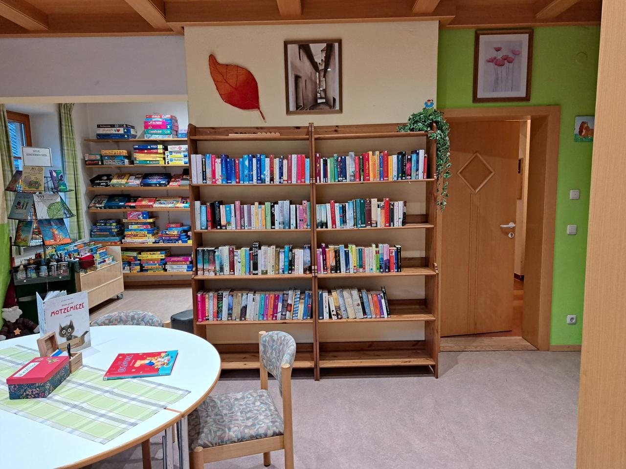 Bücherei Matrei innen: Runder Tisch mit Sessel und dahinter Regale mit Medien befüllt